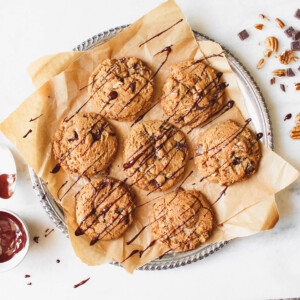 Bourbon & dark chocolate cookies on a silver tray sprinkled with sea salt and drizzled with melted chocolate.