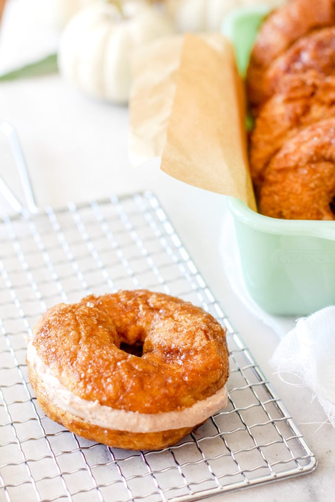 Panera Copycat Cinnamon Crunch sourdough bagel styled on a cooling rack with a jadeite dish.