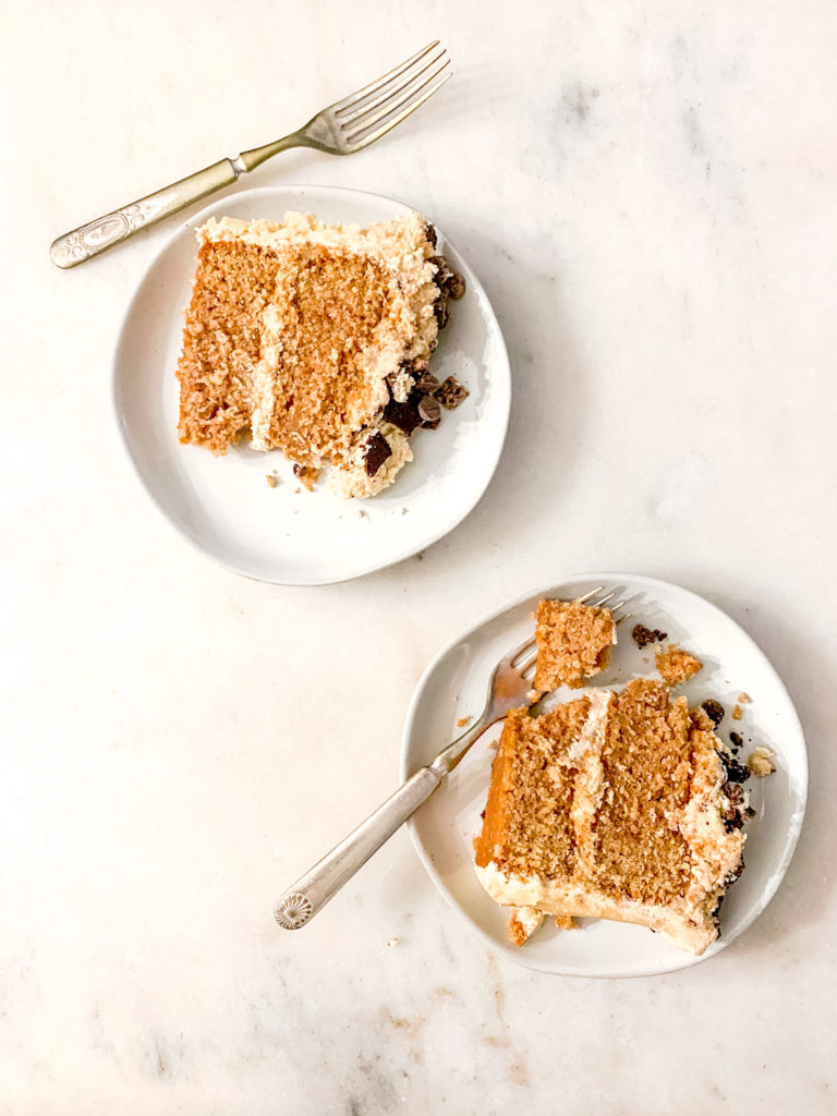Two slices of layered peanut butter cake on white pottery plates.
