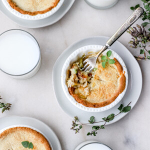 Gluten free chicken pot pies served on white pottery with fresh herbs garnishing the bowls.