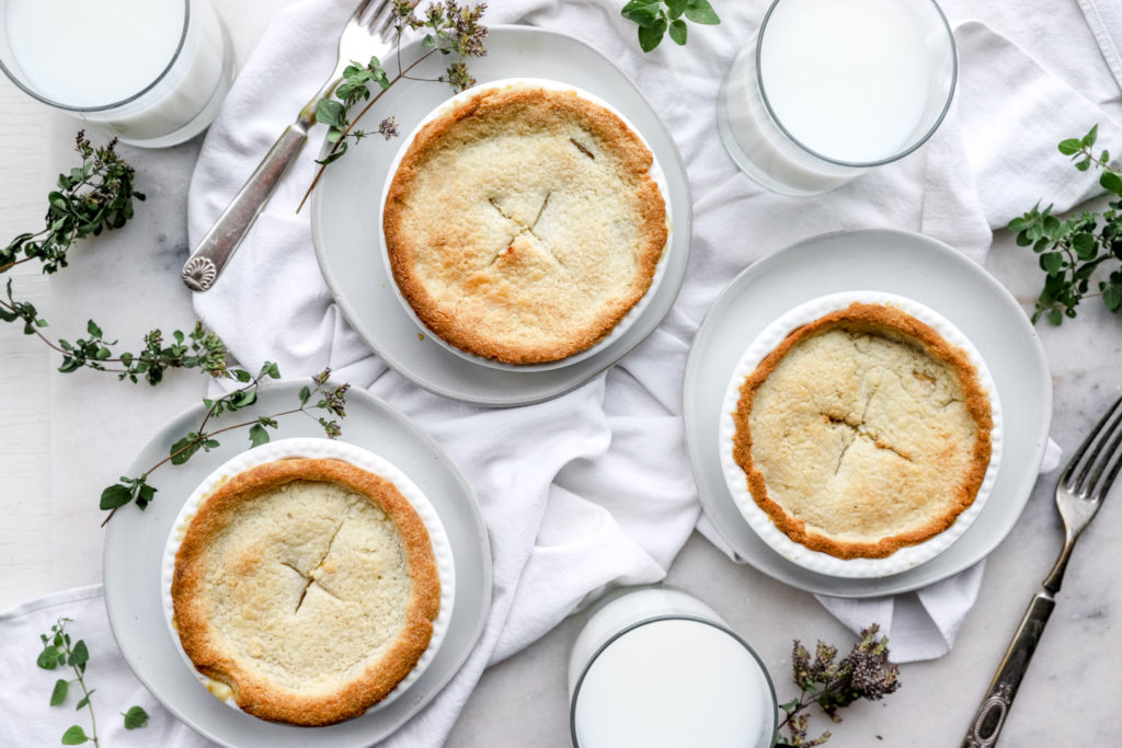 Chicken pot pie sprinkled with fresh herbs on a white tablecloth.