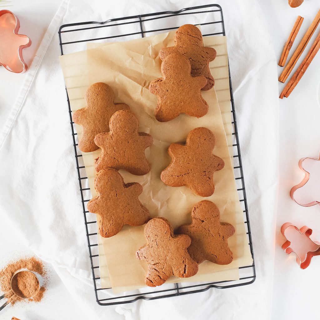 Gingerbread men on a cooling rack with cinnamon sticks.