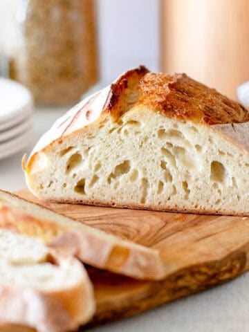 A sliced loaf of artisan sourdough bread on a cutting board.