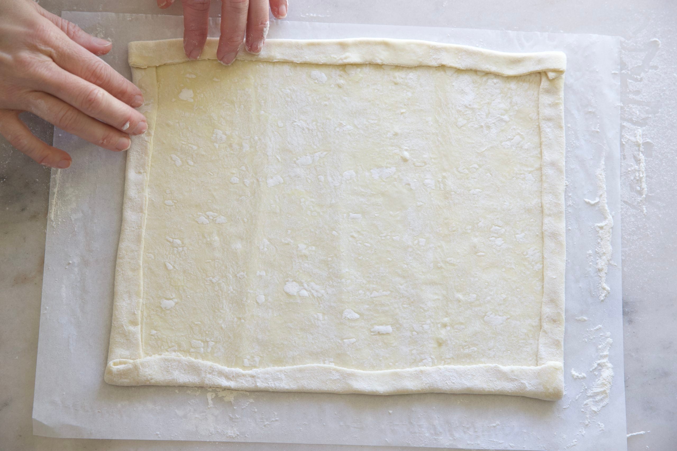 Folding the edges of a puff pastry to form a crust.