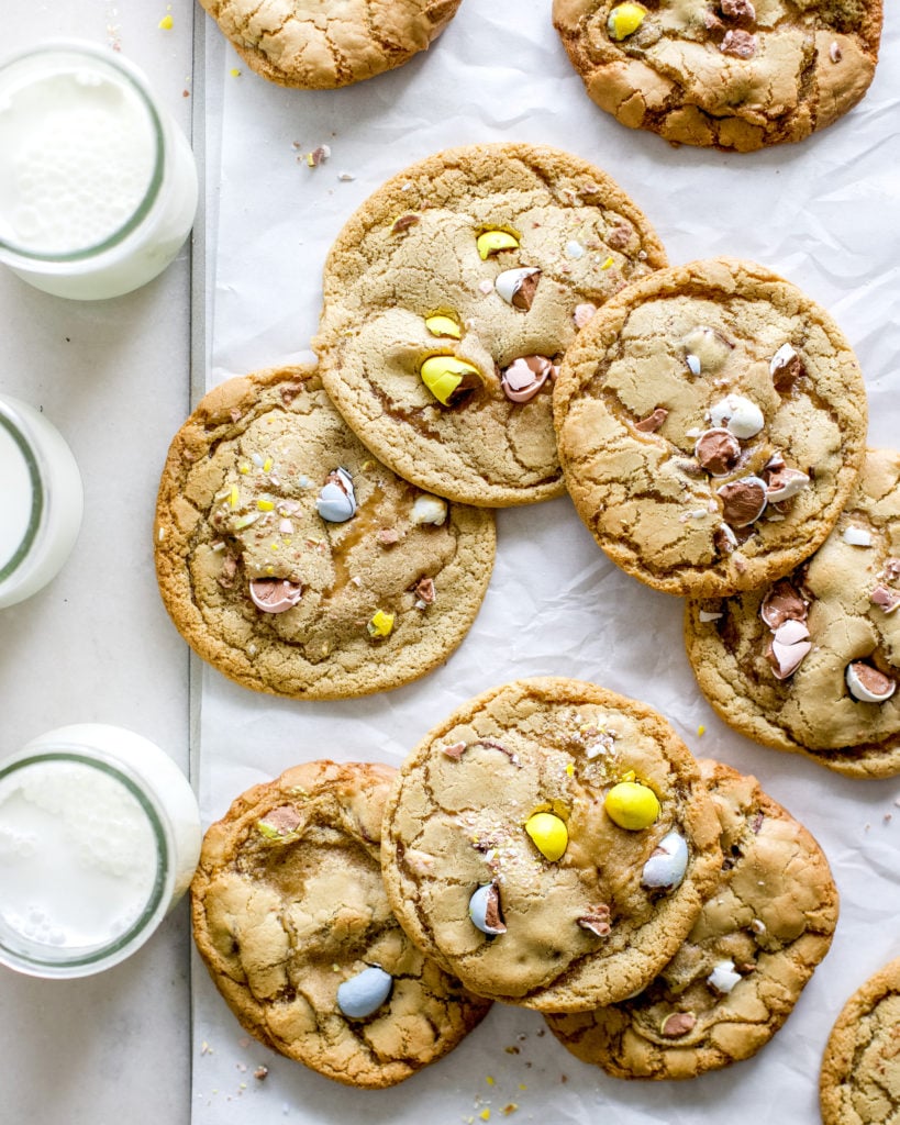 Cadbury mini egg easter cookies on a baking sheet with glasses of milk