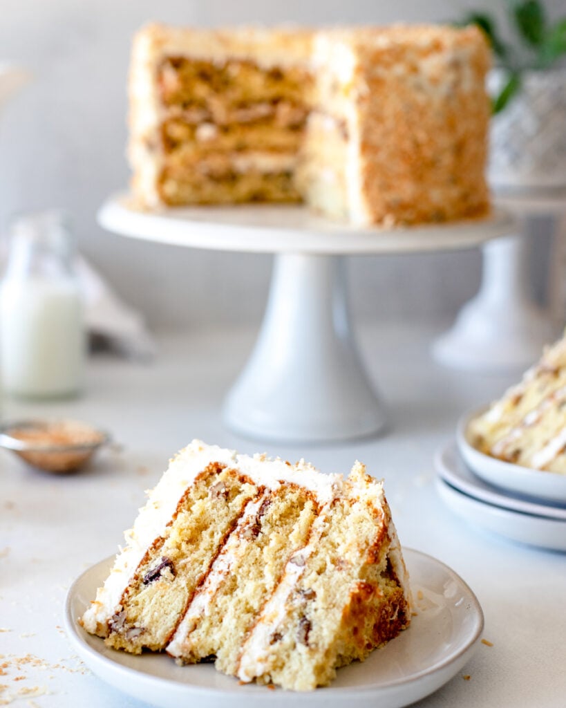 a slice of old fashioned italian cream cake positioned in front of the layered cake.