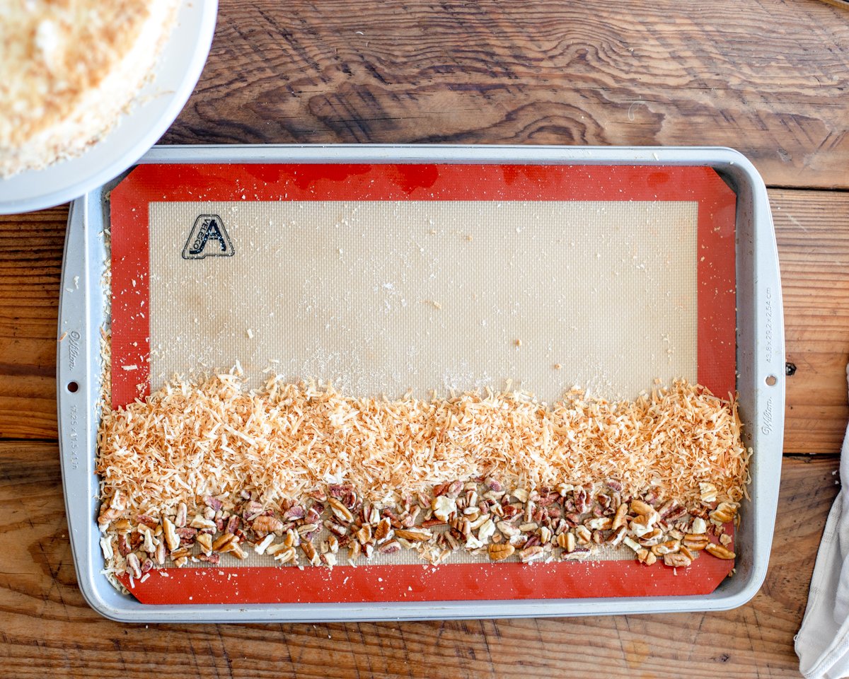 how to garnish the edges of an Italian cream cake with pecan and shredded toasted coconut on a baking sheet.