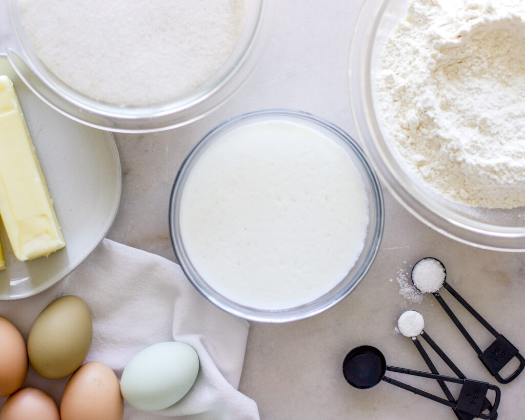 An arrangement of milk, flour, sugar, eggs, baking powder and the ingredients necessary for making a lemon bundt cake.