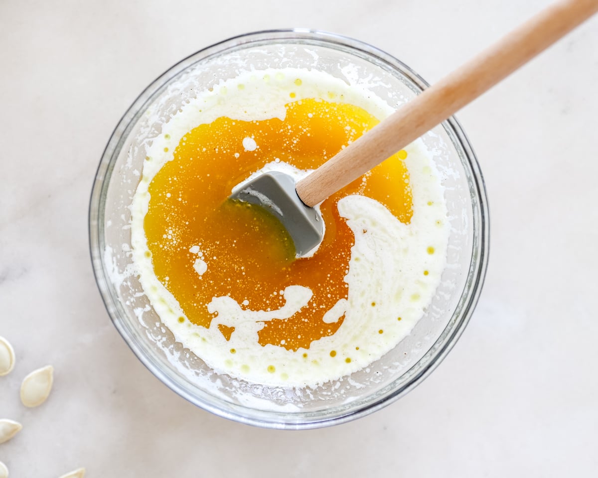 a bowl of melted butter and seasonings being stirred with a wooden spoon.