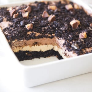 A white baking dish with a layered Oreo and peanut butter cheesecake dessert.