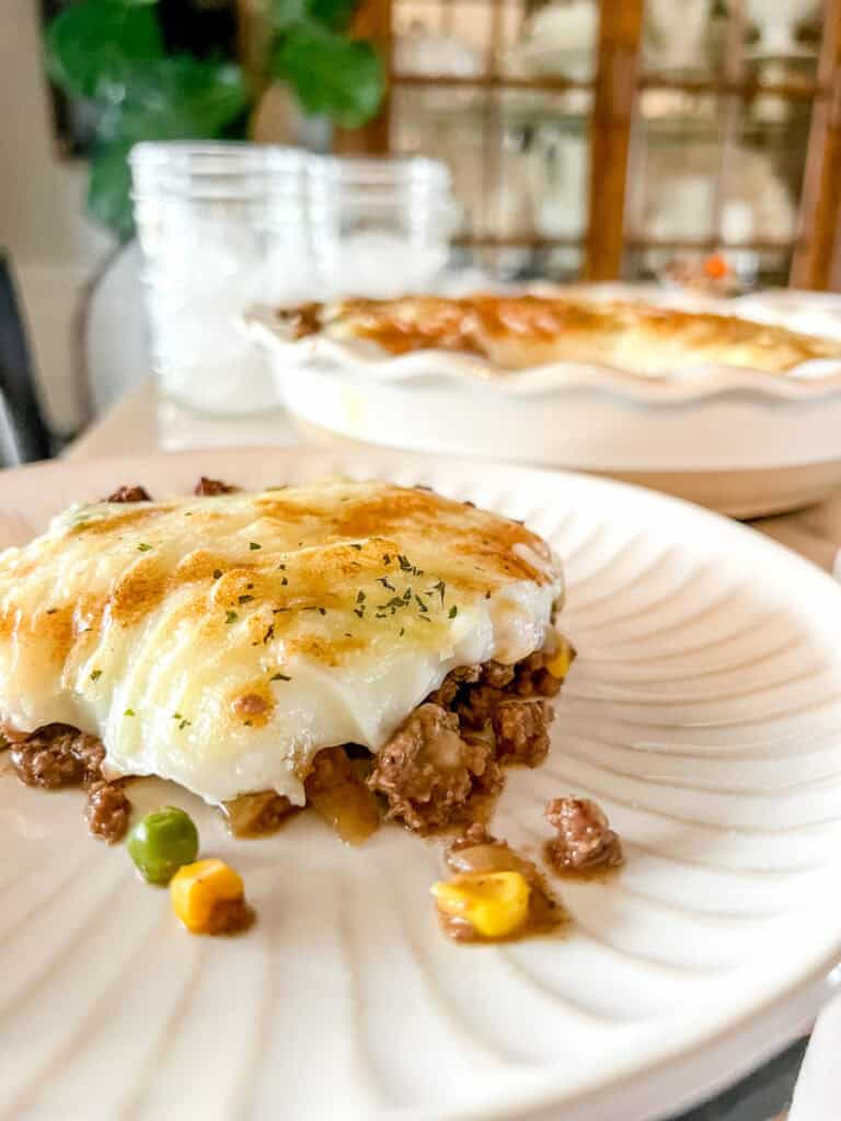 A slice of shepherd's pie on a white scalloped plate.