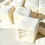A side view of a homemade marshmallow that is cut into a square shape and exposes the tasty airy marshmallow fluff inside.
