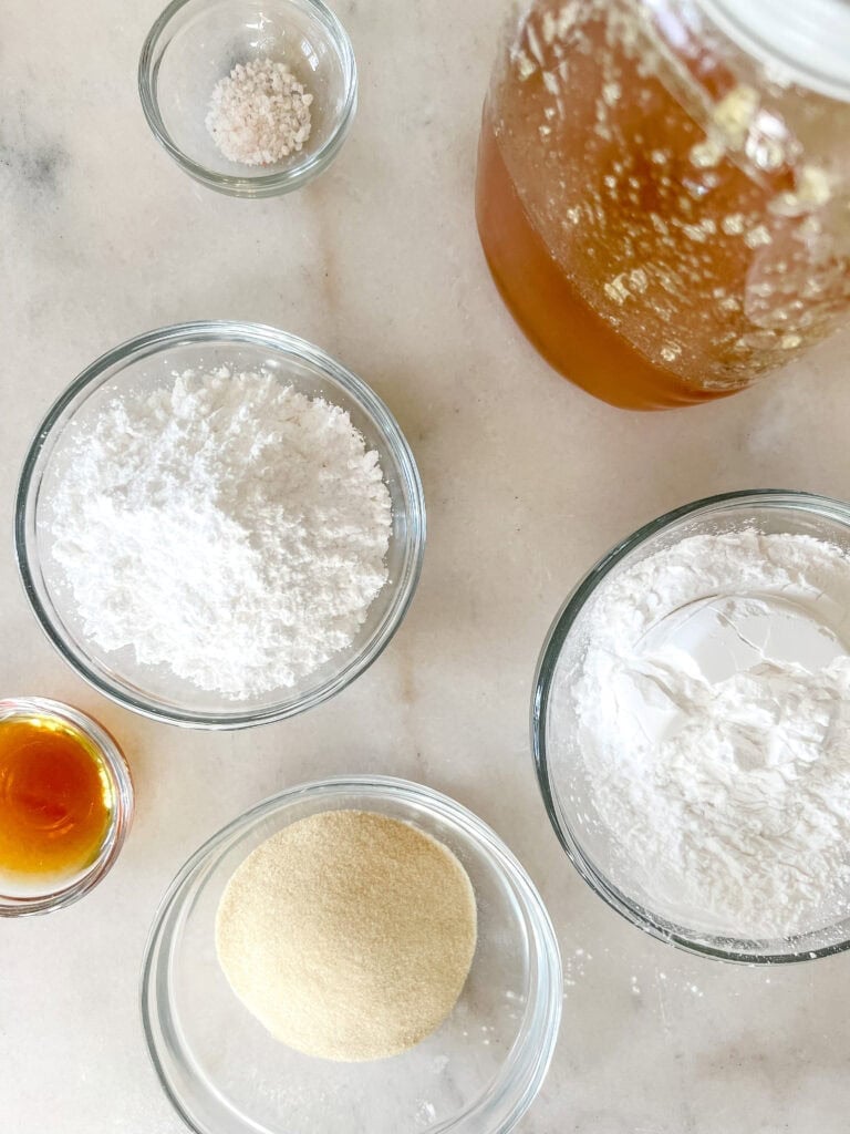 Ingredients for homemade marshmallows including honey, powdered sugar, tapioca starch, water, vanilla extract, gelatin.