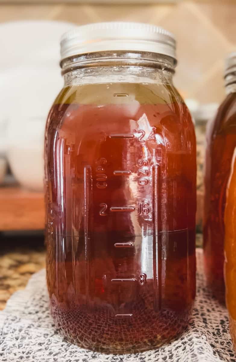A quart mason jar of pressure canned chicken bone broth with a rich brown color.