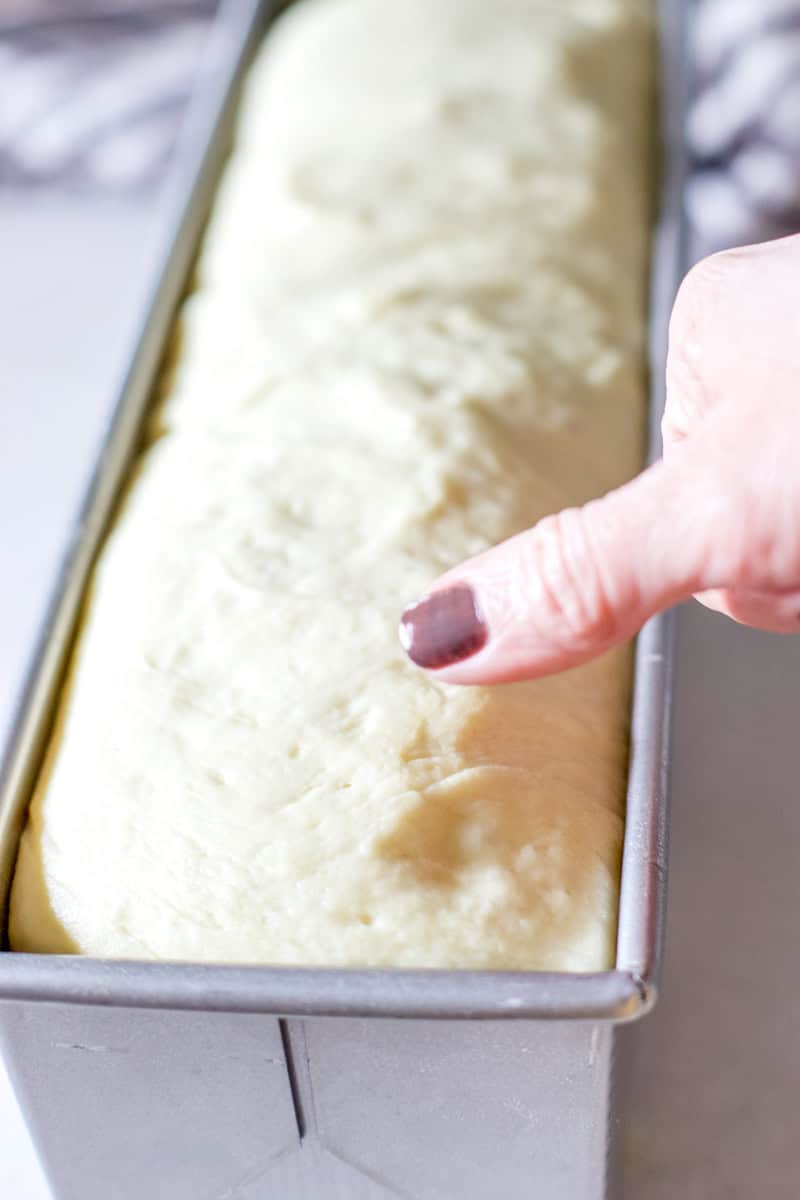 This is a picture of the baker pushing her thumb into the corner of the unbaked bread to see if it is finished proofing and ready to be baked by watching the indentation.