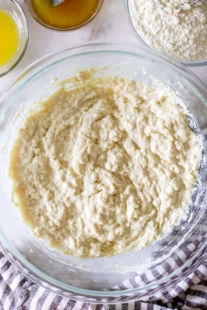 Making a sponge by combining part of the flour, honey, water and yeast for a big loaf of sandwich bread, step one.