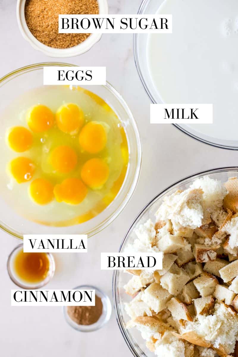 A top view of the ingredients for sourdough bread pudding including eggs, brown sugar, milk, vanilla, cinnamon all in glass prep bowls.