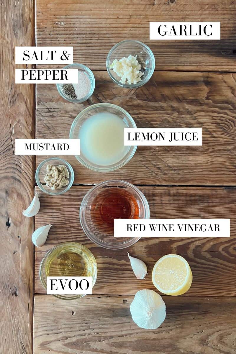 A flat lay of ingredients for an all-purpose venison marinade including mustard, lemon juice, red wine vinegar, garlic and salt and pepper.