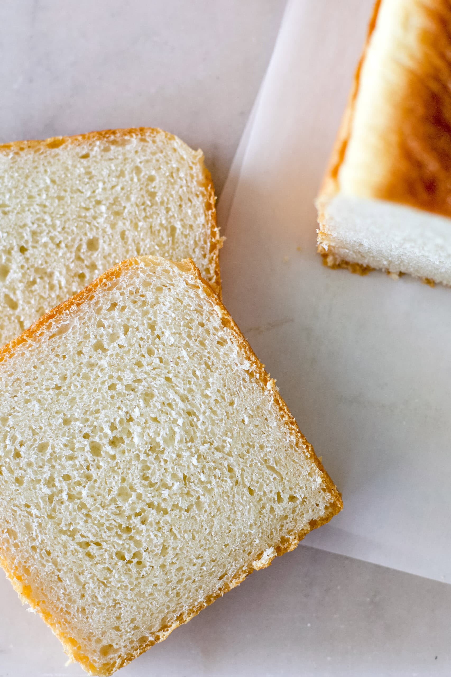 Slices of sourdough bread baked in a pullman loaf pan on a white background.