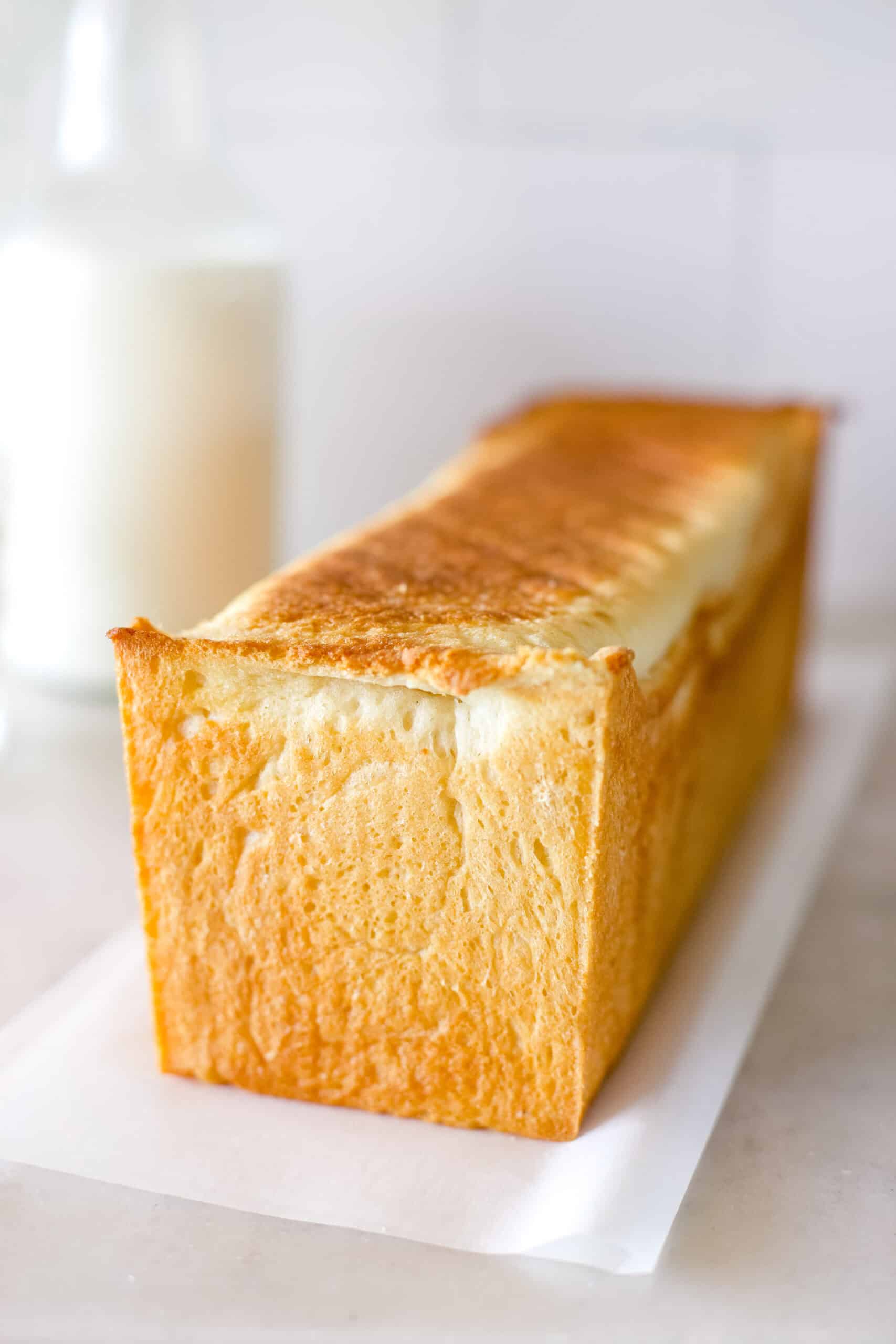 A freshly baked loaf of sourdough sandwich bread pain de mie cooling on a parchment paper.