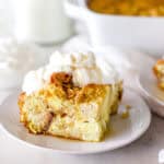 An up close image of a slice of bread pudding with whipped topping and caramel sauce