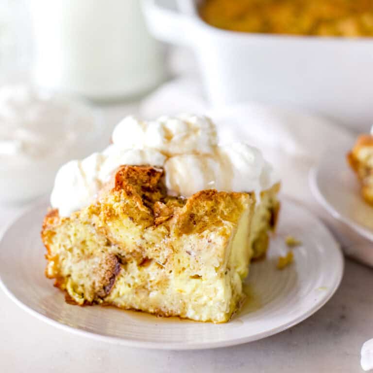 An up close image of a slice of bread pudding with whipped topping and caramel sauce