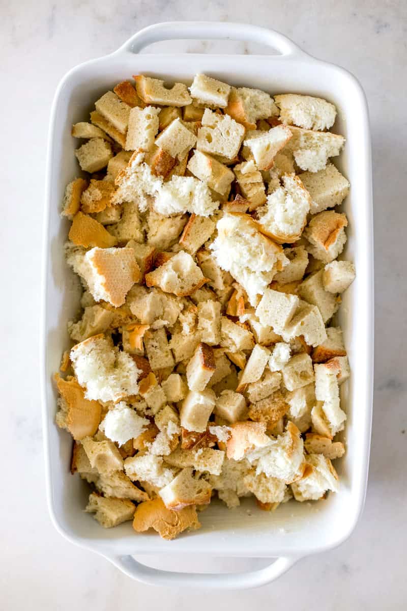 Step one of making sourdough bread pudding: Tear or cut the bread into 1 inch pieces. Grease a 9X13 baking dish and pour the bread pieces into the dish in an even layer.