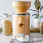 A picture of a mock mill grain mill with wheat berries in a jar and freshly milled flour in a bowl.