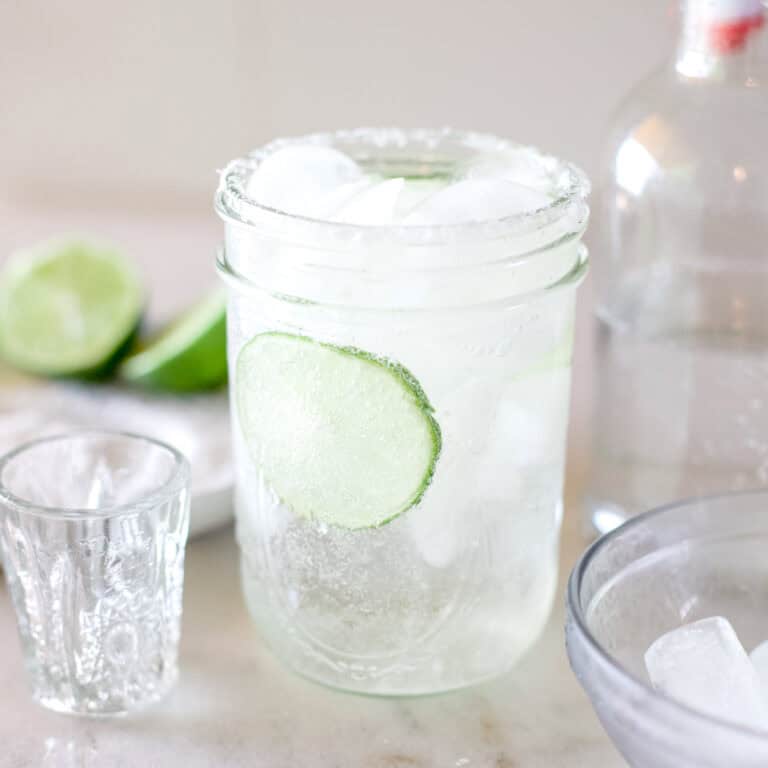 A close-up view of a ranch water cocktail made with lime and tequila served in a mason jar with ice.