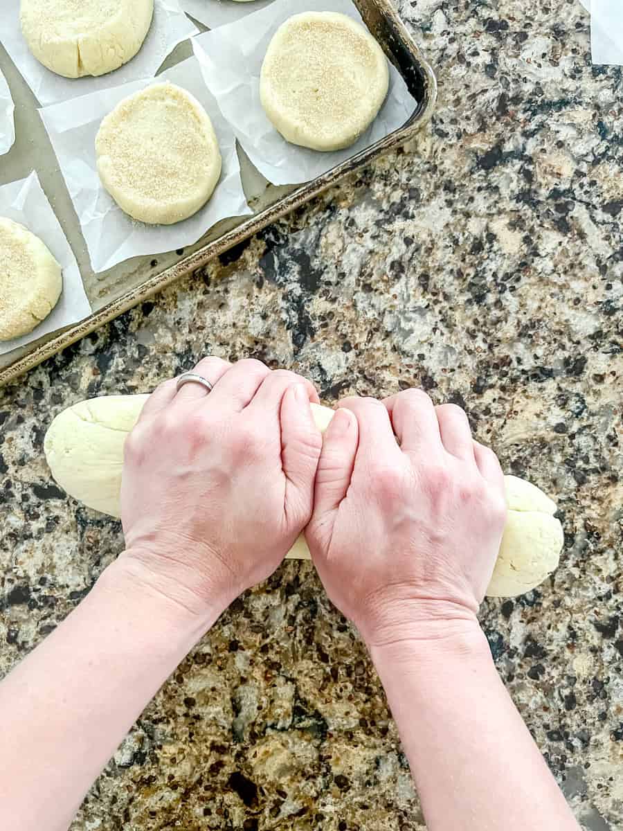 Step four of making sourdough English muffins rolling the dough into a long cylinder to cut with dental floss.
