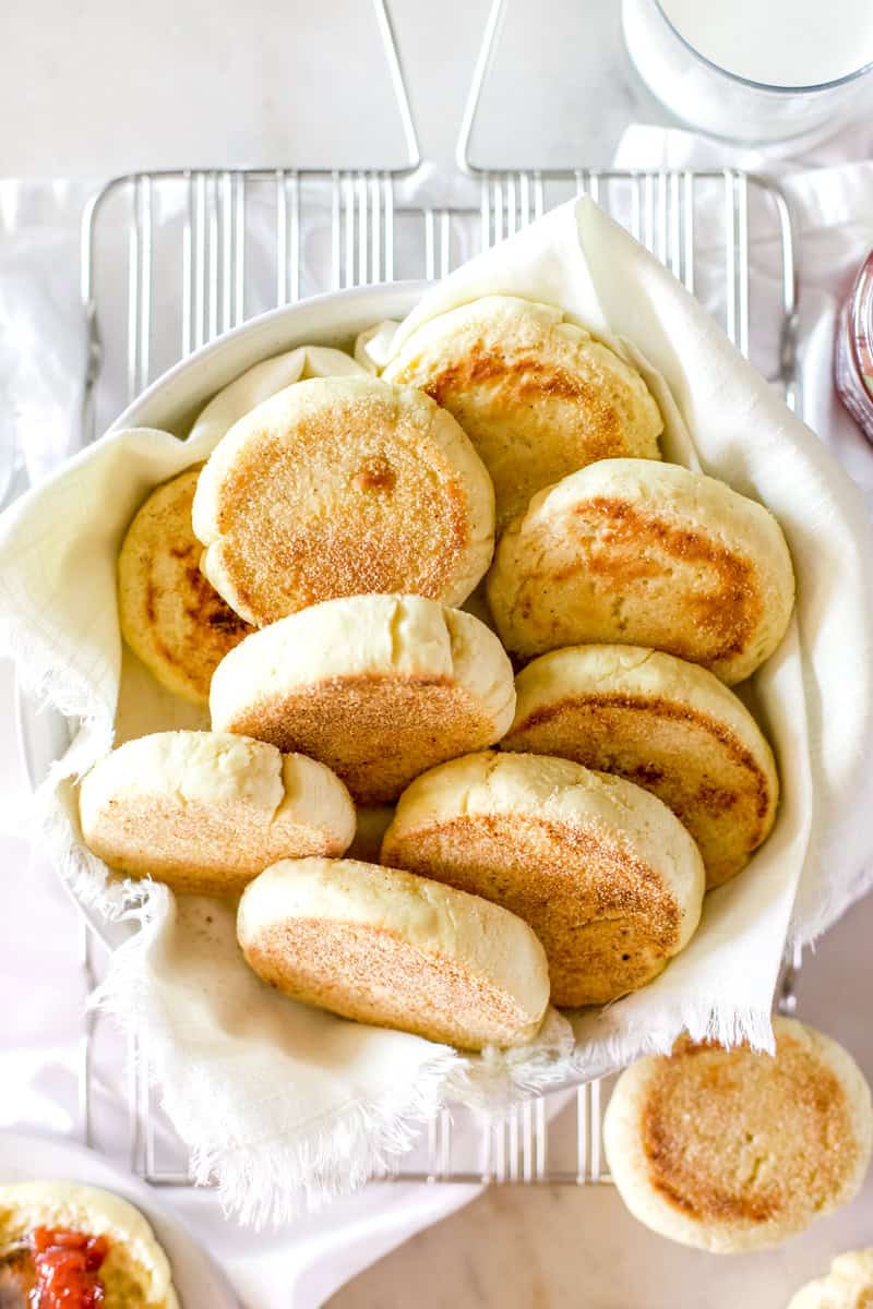 A bowl of fresh baked sourdough English muffins.