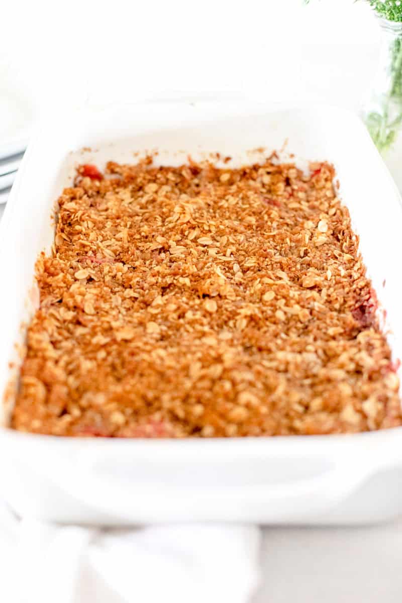 A baked strawberry rhubarb crisp in a white baking dish.