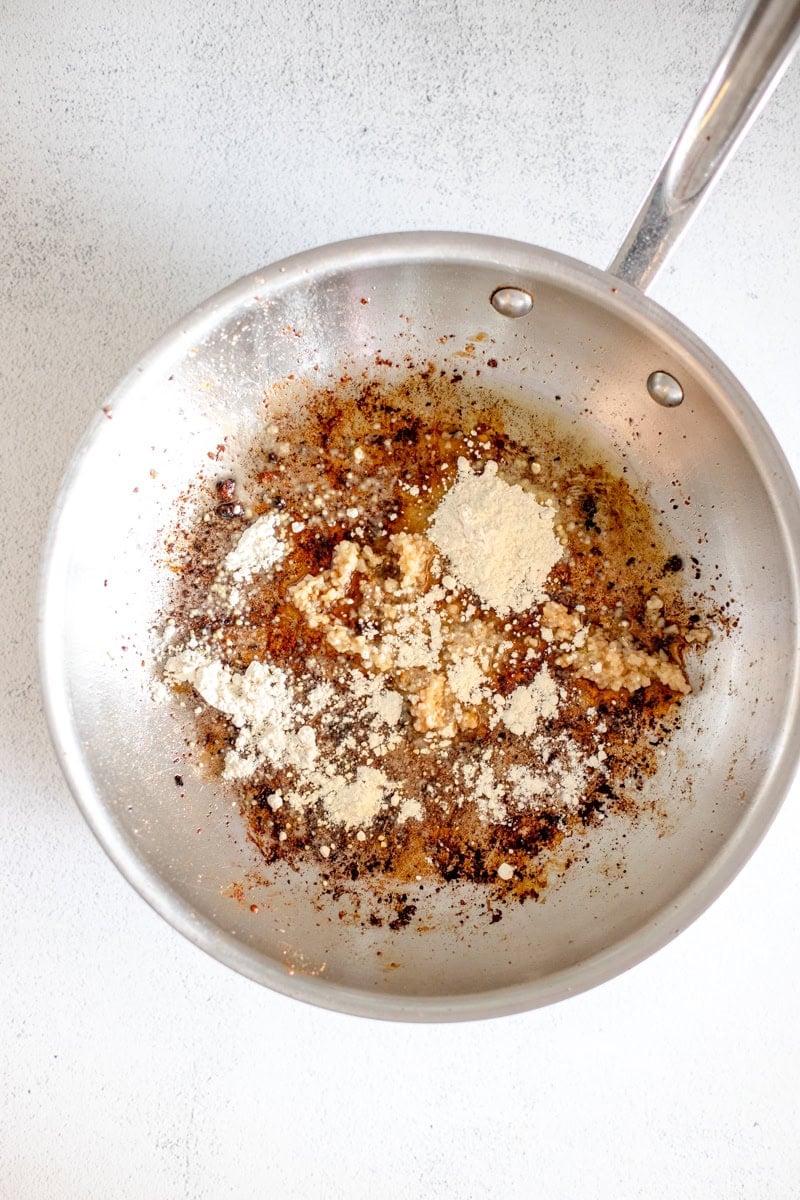 Step two of making Loaded Marry Me Chicken pasta is removing the cooked chicken from the pan and adding flour and butter to make the cream sauce.