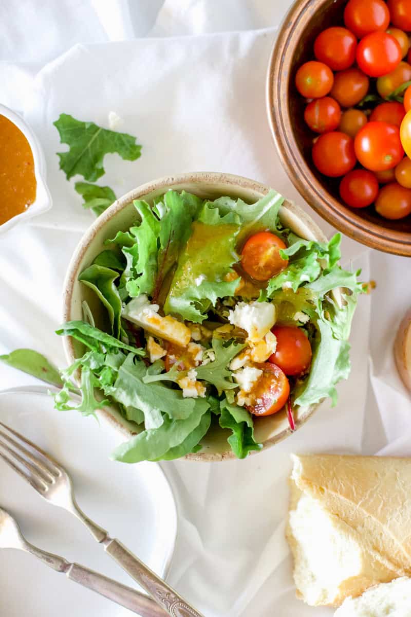 A leafy bowl of spring greens and apricot dressing served with cherry tomatoes.