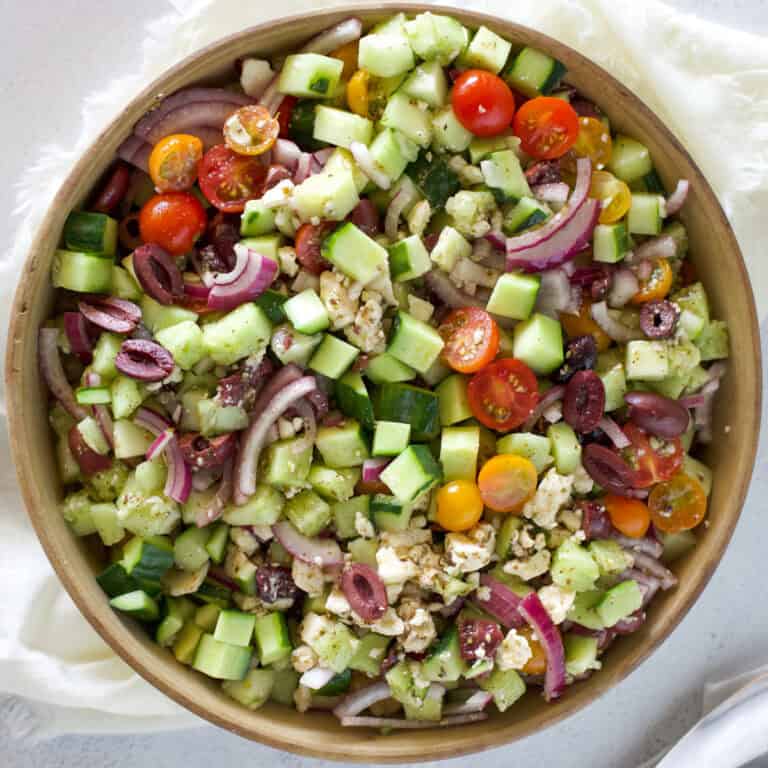 Tomato Cucumber Feta Salad cover photo a top view of the salad in a shallow stoneware bowl.