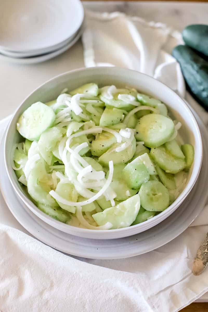 A bowl of cucumber salad that is finished and ready to be served from a white bowl.