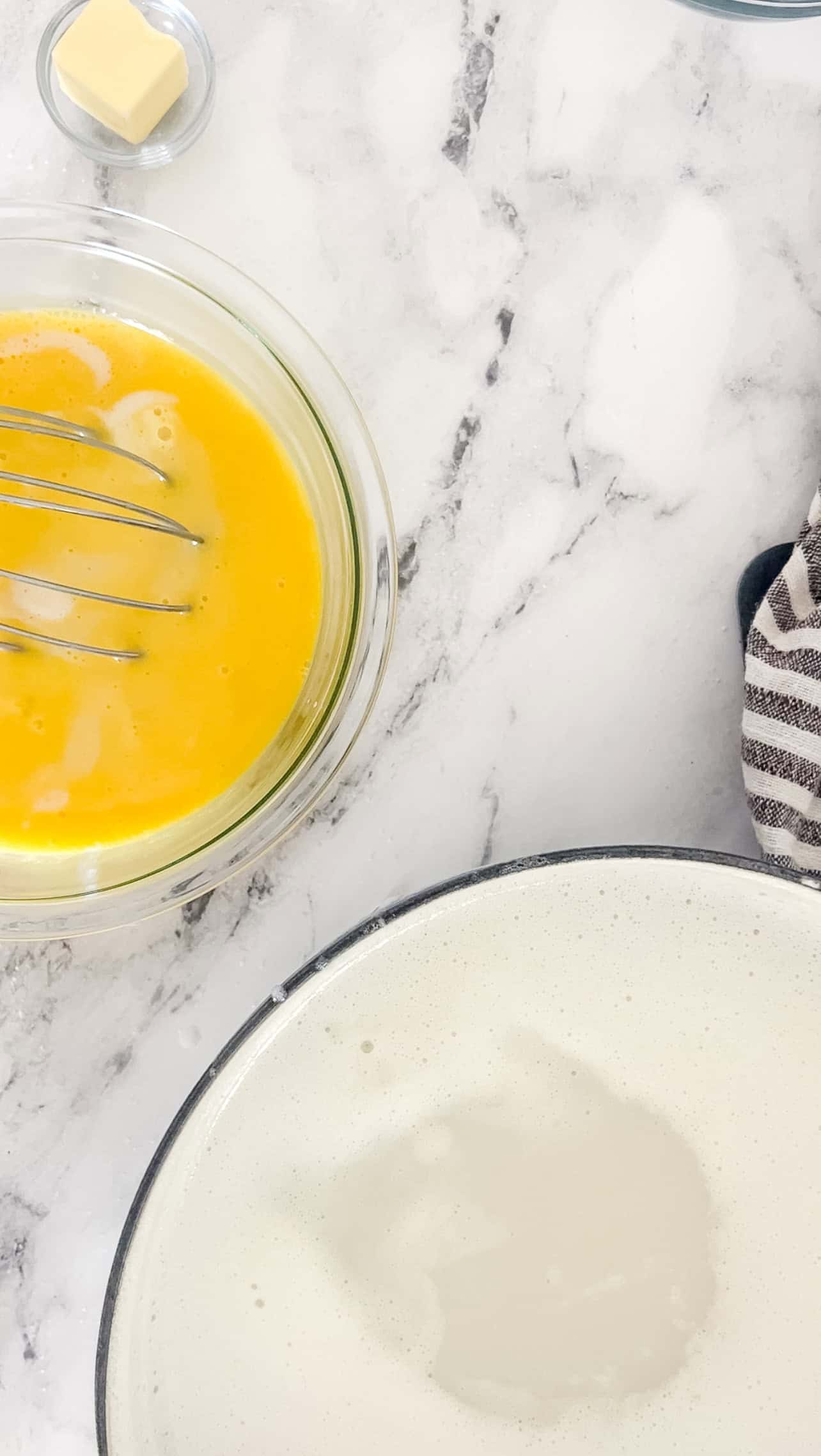 Step two of making homemade vanilla pudding is tempering the egg with the hot milk mixture by adding in the milk and whisking.