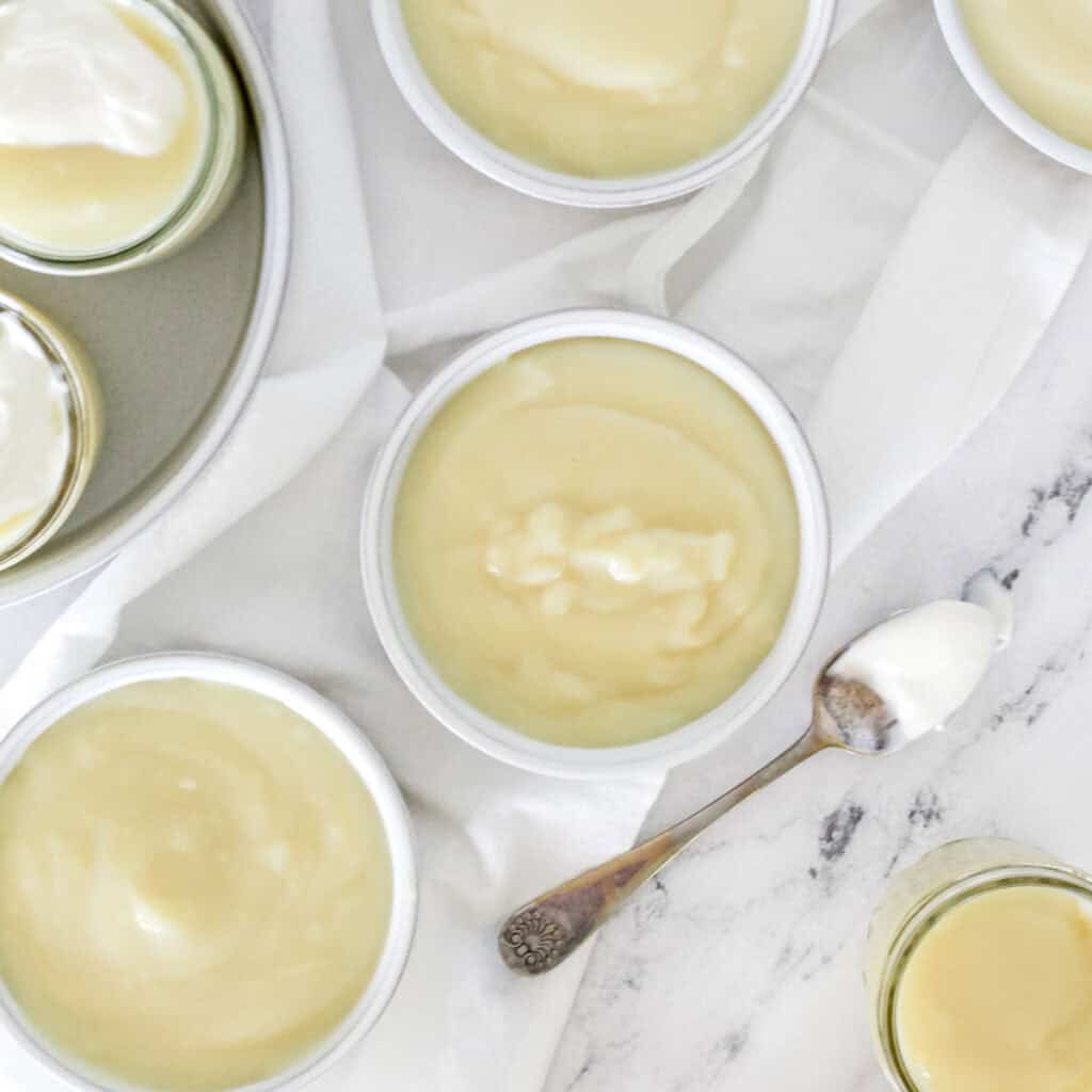 Bowls of homemade vanilla pudding on a marble background.