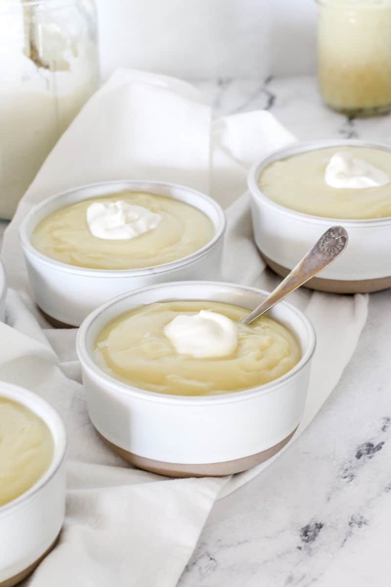 Bowls of homemade pudding on a marble background with dollops of whipped topping.