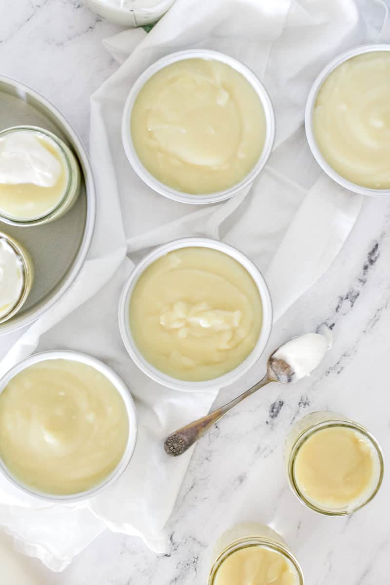 Bowls of homemade pudding on a marble background with dollops of whipped topping.