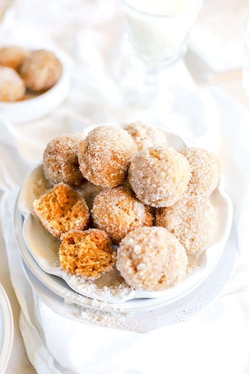 A plate of pumpkin spice donut holes with one pulled apart to show the moist inside.