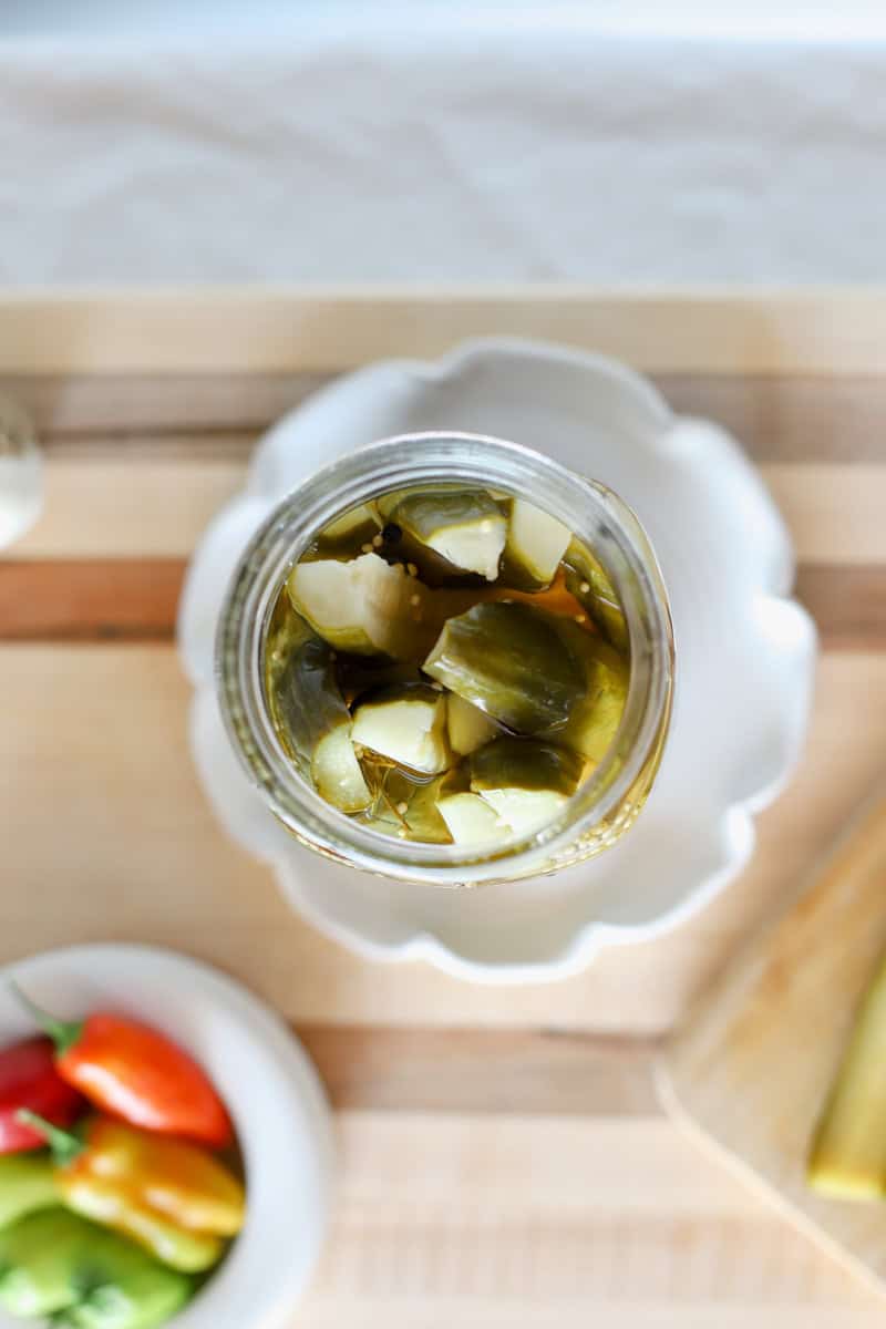 A jar of homemade pickles (easy cucumber recipe) looking at an open jar of dill spears from above.