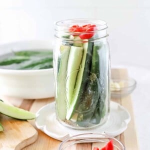 A jar of cucumber pickles that is ready to have the brine poured over and be canned.