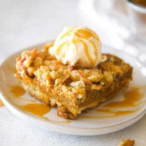 A slice of pumpkin crunch cake (no cake mix!) on a white plate served ala mode.