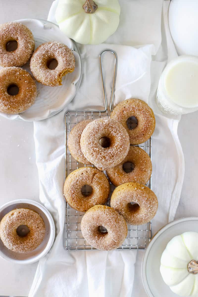 A cooling rack with pumpkin spice donuts cooling on a white background.