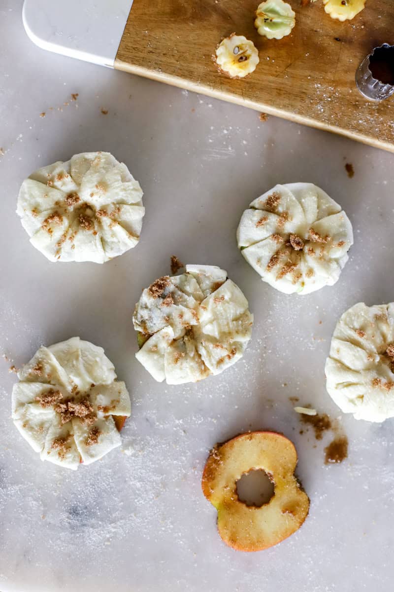 Wrap the dough around the apple and brush with butter before baking.