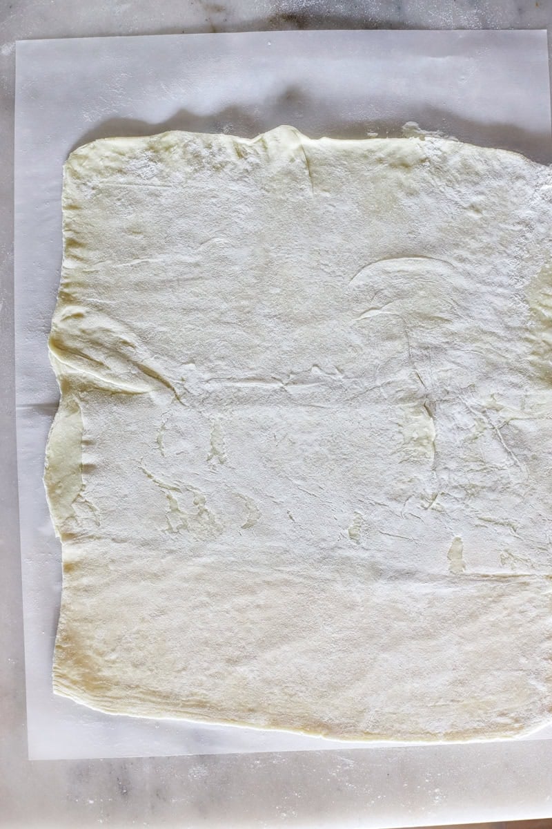 Step one of making an apple puff pastry is Gently unfold the thawed puff pastry onto an area lightly dusted with flour.  Carefully roll the pastry dough to a 10 x 11 inch rectangle. Transfer the puff pastry to the lined baking sheet. 