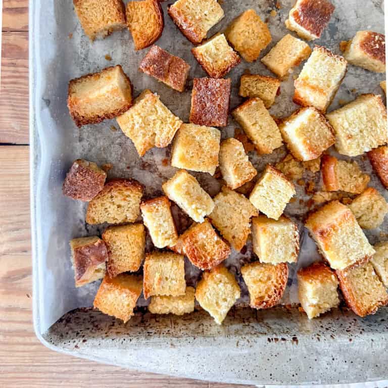 A close up view of sourdough croutons on a baking sheet.