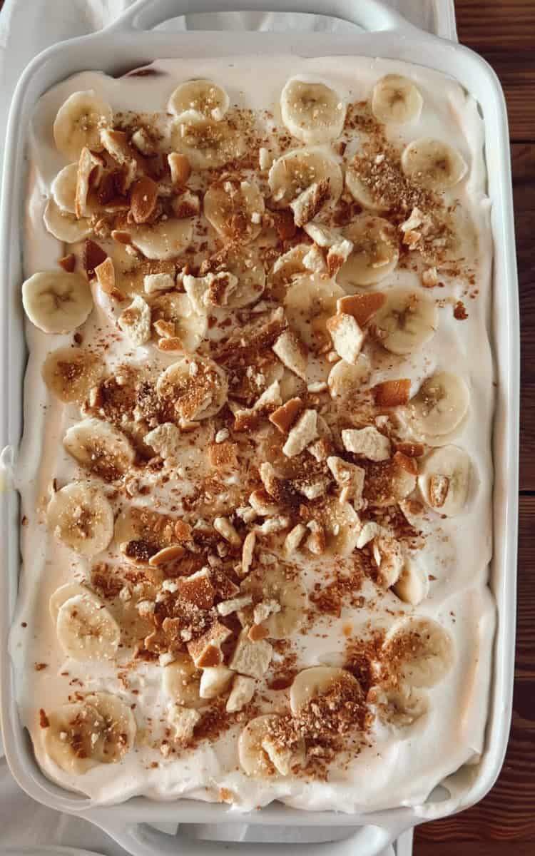 Step 5 of making nilla wafer banana pudding is adding crushed wafers and banana slices on top.