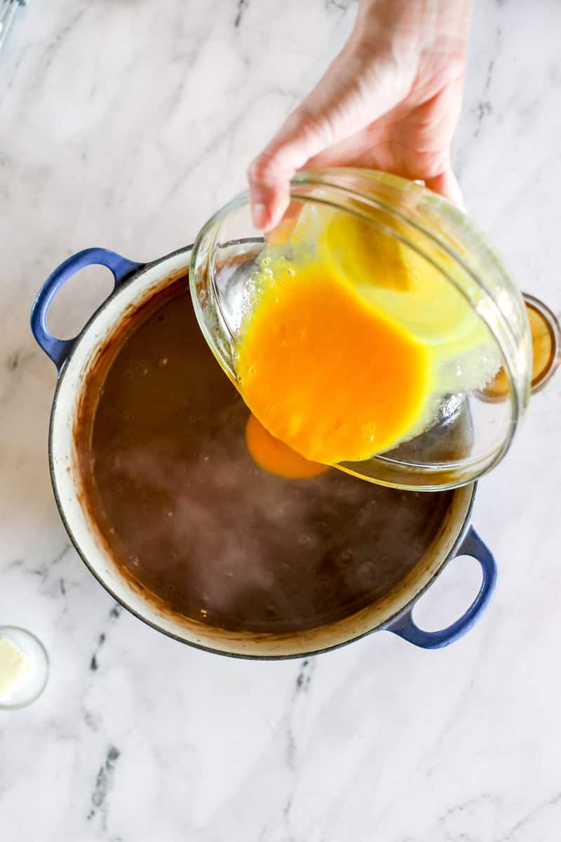Tempered eggs being poured into chocolate pudding.